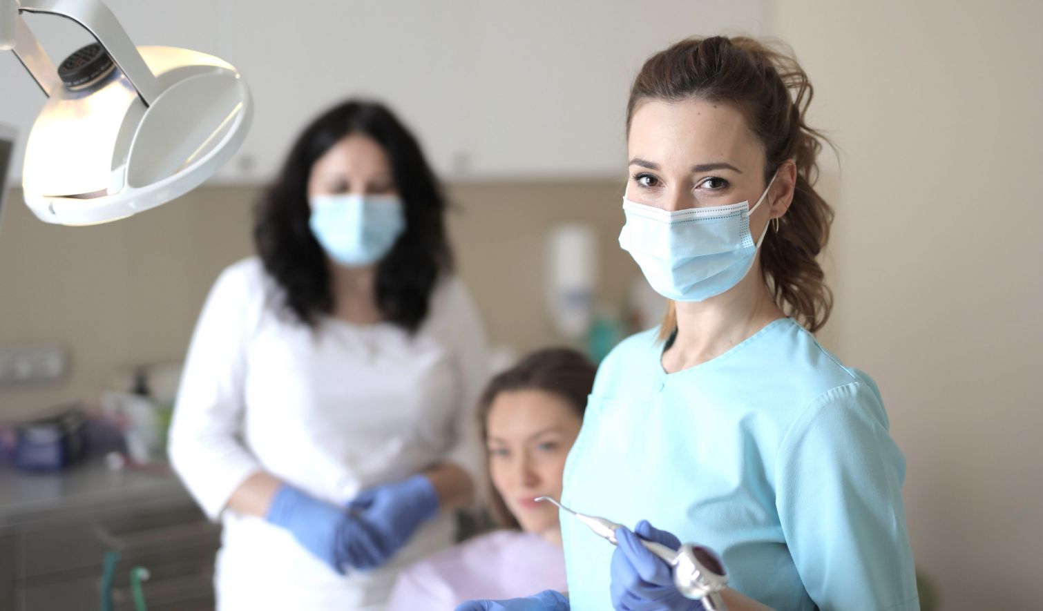 Zahnärztin schaut in die Kamera und Patientin auf dem Stuhl